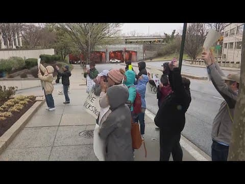 Fired Department of Education workers collect belongings while small crowd shows support
