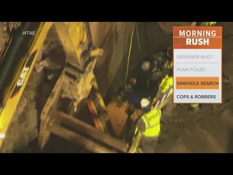 Rescuers working to save a woman who fell into a sinkhole