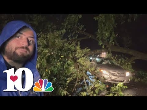 Knox County Residents maneuver under a fallen tree as it blocks the roadway