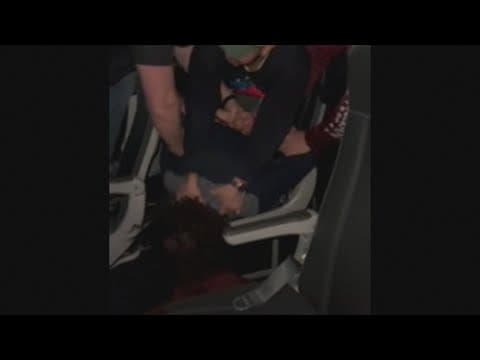 Passengers hold down a man after he began throwing punches and cracking a window