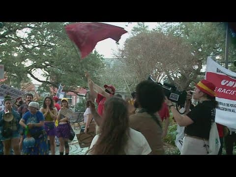 People protest as President Trump arrives in New Orleans for historic Super Bowl visit