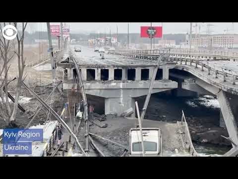 People walk over bridge wreckage in Kyiv region to evacuate