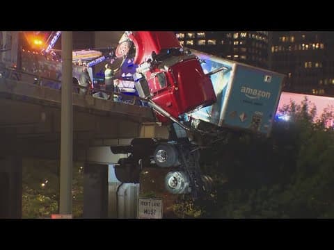 An Amazon 18-wheeler dangles off a bridge in downtown Dallas