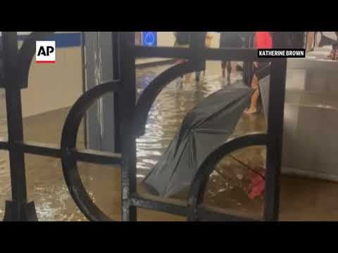 Subway passengers walk in flood waters in New York train station
